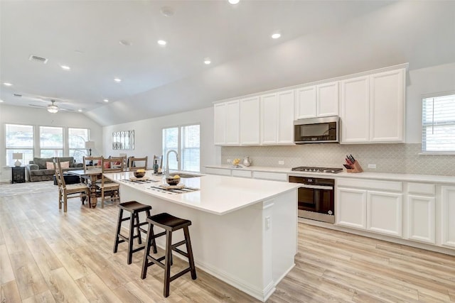 112 Silver Ridge Dr, Georgetown, TX 78633 - kitchen featuring stainless steel appliances, a kitchen island with sink, lofted ceiling, light wood finished floors, and backsplash