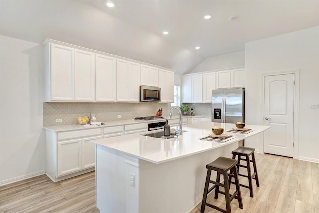 112 Silver Ridge Dr, Georgetown, TX 78633 - kitchen with appliances with stainless steel finishes, tasteful backsplash, light wood-type flooring, white cabinetry, and vaulted ceiling