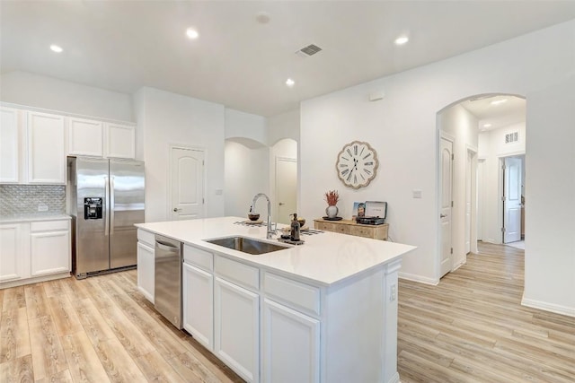 112 Silver Ridge Dr, Georgetown, TX 78633 - kitchen featuring appliances with stainless steel finishes, arched walkways, light wood-type flooring, an island with sink, and recessed lighting