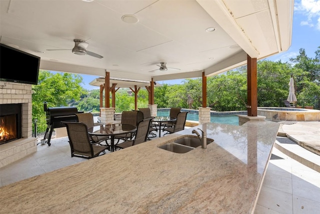 22126 Briarcliff Dr, Spicewood, TX 78669 - view of patio / terrace with an outdoor brick fireplace, a ceiling fan, an outdoor pool, outdoor dining space, and view of scattered trees
