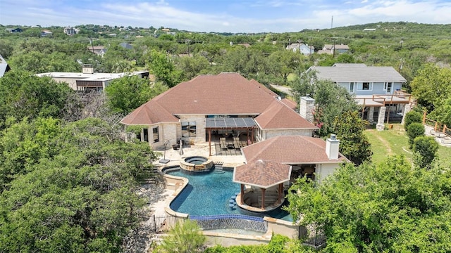 22126 Briarcliff Dr, Spicewood, TX 78669 - rear view of house with a pool with connected hot tub, a chimney, stone siding, and a patio