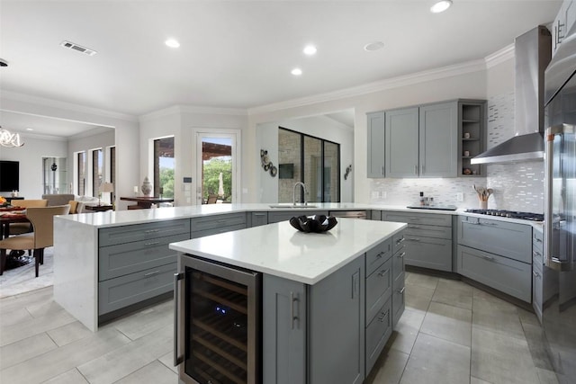22126 Briarcliff Dr, Spicewood, TX 78669 - kitchen featuring gray cabinets, beverage cooler, wall chimney exhaust hood, a peninsula, and a center island
