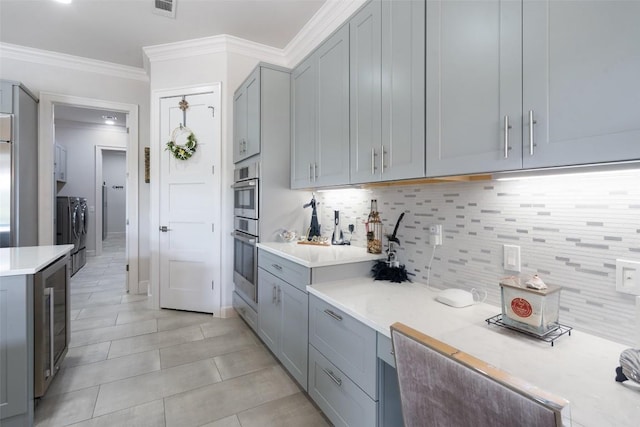 22126 Briarcliff Dr, Spicewood, TX 78669 - kitchen featuring washing machine and clothes dryer, wine cooler, light countertops, tasteful backsplash, and crown molding