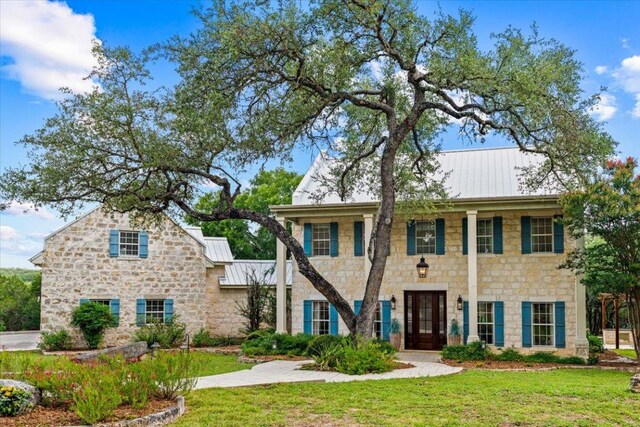 1660 W Mccarty Ln, San Marcos, TX 78666 - view of front of house featuring stone siding, a standing seam roof, a front yard, and a metal roof