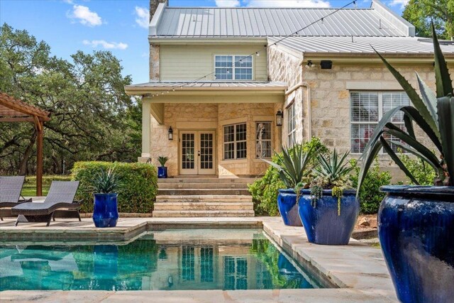 1660 W Mccarty Ln, San Marcos, TX 78666 - rear view of property with french doors, stone siding, a metal roof, an outdoor pool, and a patio area