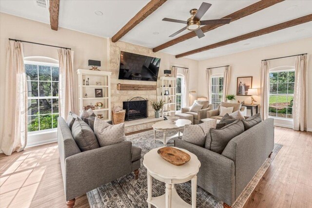 1660 W Mccarty Ln, San Marcos, TX 78666 - living area featuring healthy amount of natural light, beam ceiling, a large fireplace, ceiling fan, and light wood-style flooring