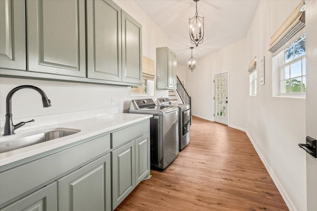 1660 W Mccarty Ln, San Marcos, TX 78666 - laundry area featuring washer and dryer, cabinet space, light wood-style flooring, and a chandelier