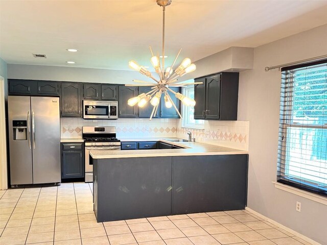 4202 Kilgore Ln, Austin, TX 78727 - kitchen featuring appliances with stainless steel finishes, a chandelier, decorative backsplash, a peninsula, and light tile patterned floors