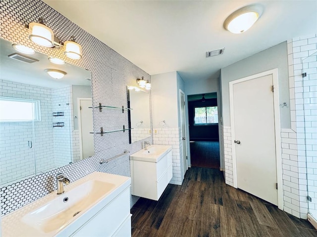 4202 Kilgore Ln, Austin, TX 78727 - full bathroom featuring tile walls, a shower stall, wood finished floors, two vanities, and a wainscoted wall