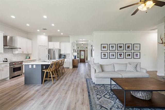 300 Errol Dr, Spicewood, TX 78669 - living area featuring crown molding, a ceiling fan, arched walkways, light wood-type flooring, and recessed lighting