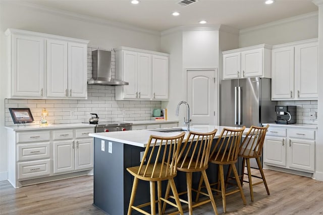 300 Errol Dr, Spicewood, TX 78669 - kitchen with wall chimney range hood, freestanding refrigerator, a center island with sink, ornamental molding, and tasteful backsplash