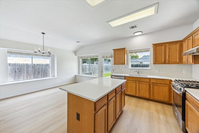 3659 Nolan Ryan Blvd, Round Rock, TX 78665 - kitchen featuring stainless steel range with gas stovetop, light wood-style flooring, brown cabinetry, backsplash, and lofted ceiling