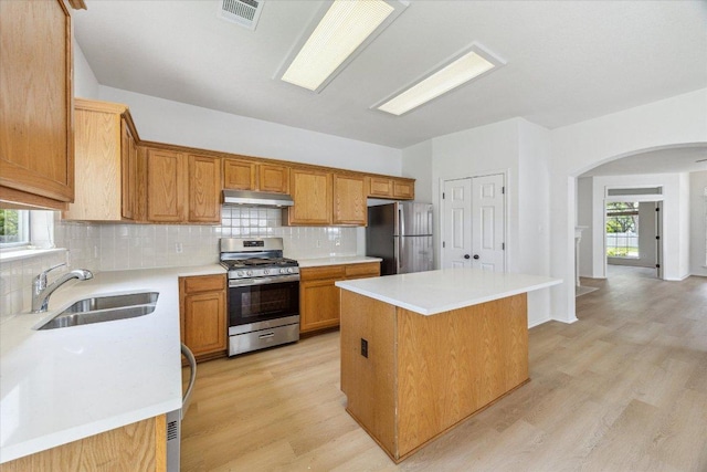 3659 Nolan Ryan Blvd, Round Rock, TX 78665 - kitchen with appliances with stainless steel finishes, arched walkways, under cabinet range hood, a center island, and tasteful backsplash