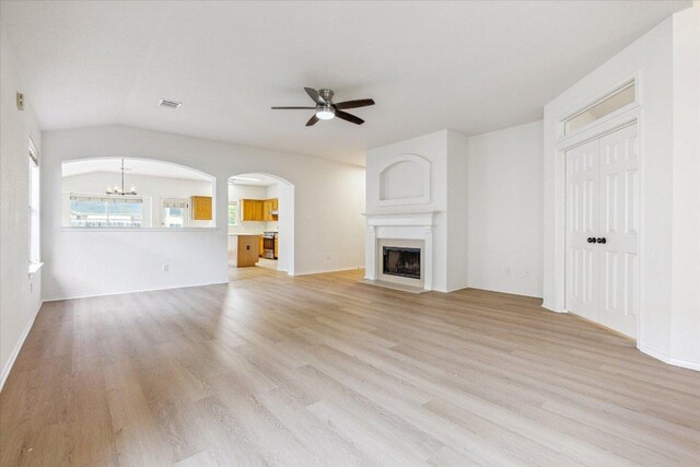 3659 Nolan Ryan Blvd, Round Rock, TX 78665 - unfurnished living room featuring a ceiling fan, light wood-type flooring, arched walkways, a chandelier, and lofted ceiling
