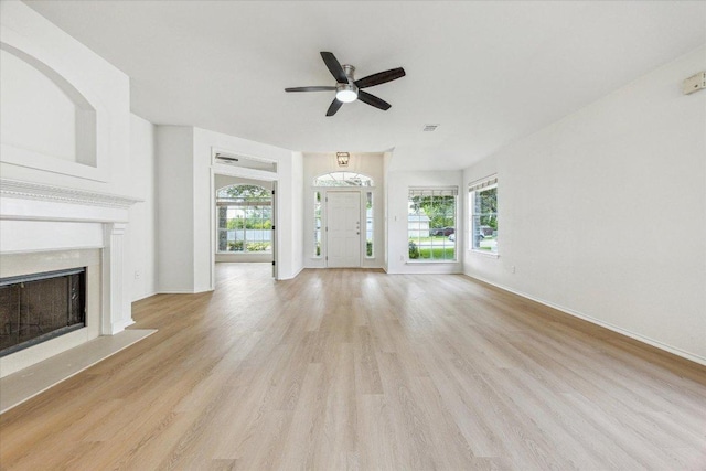 3659 Nolan Ryan Blvd, Round Rock, TX 78665 - unfurnished living room with light wood-style flooring, ceiling fan, and a fireplace with flush hearth