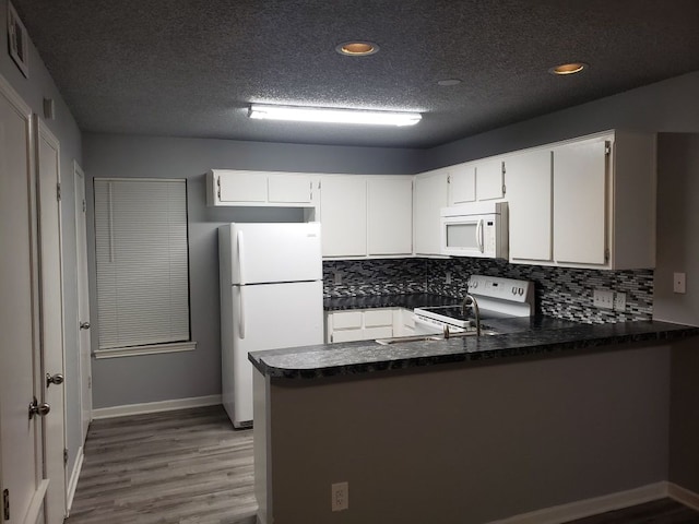 1221 W Hopkins St Unit 11, San Marcos, TX 78666 - kitchen featuring white appliances, dark countertops, a peninsula, wood finished floors, and recessed lighting