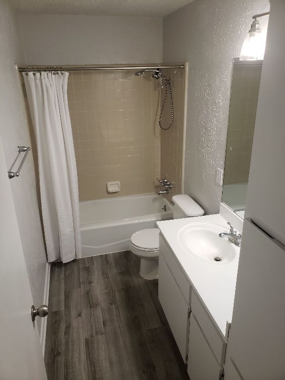 1221 W Hopkins St Unit 11, San Marcos, TX 78666 - full bath featuring a textured wall, shower / tub combo with curtain, vanity, and wood finished floors