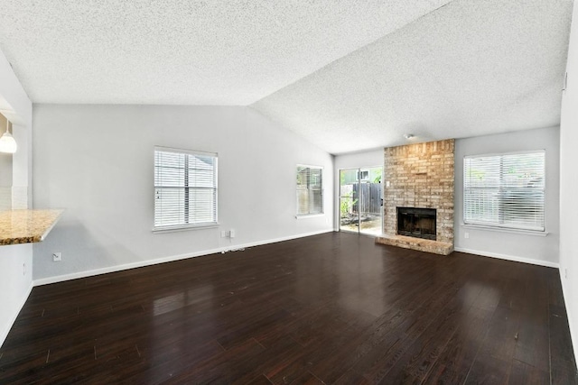 4614 Ganymede Dr, Austin, TX 78727 - unfurnished living room with wood finished floors, a textured ceiling, a brick fireplace, and lofted ceiling