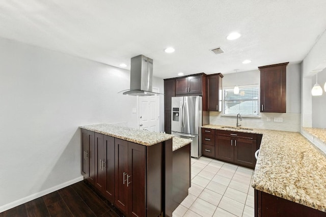 4614 Ganymede Dr, Austin, TX 78727 - kitchen featuring island exhaust hood, stainless steel fridge, a peninsula, light stone countertops, and dark brown cabinetry