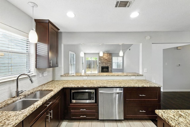 4614 Ganymede Dr, Austin, TX 78727 - kitchen with stainless steel appliances, decorative light fixtures, tasteful backsplash, light stone countertops, and dark brown cabinetry