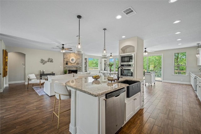 1621 Angolo, New Braunfels, TX 78132 - kitchen featuring stainless steel appliances, ceiling fan, a stone fireplace, dark wood-style flooring, and recessed lighting