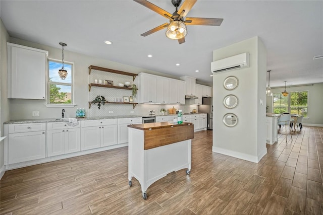 1621 Angolo, New Braunfels, TX 78132 - kitchen with a wall mounted air conditioner, butcher block counters, white cabinets, light wood finished floors, and recessed lighting