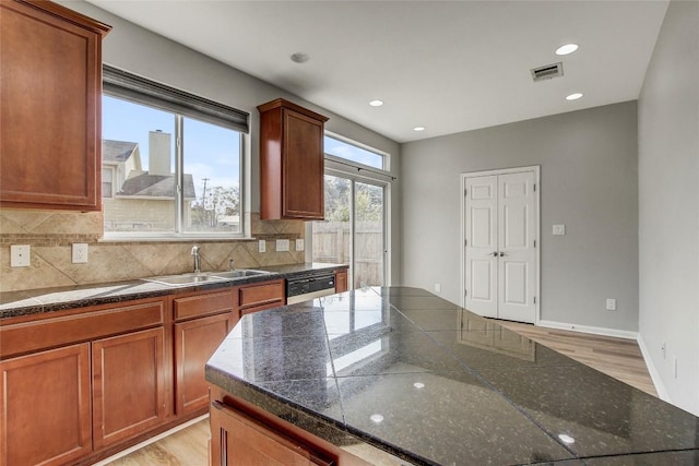 512 Eberhart Ln Unit 1207, Austin, TX 78745 - kitchen featuring light wood finished floors, backsplash, brown cabinetry, stainless steel dishwasher, and recessed lighting