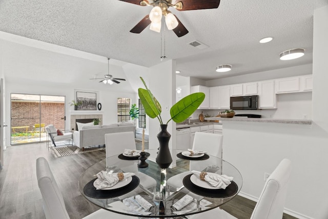 800 Saunders Dr, Round Rock, TX 78664 - dining room featuring ceiling fan, a textured ceiling, wood finished floors, a fireplace, and recessed lighting