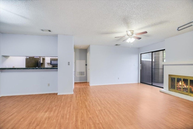 1202 Thorpe Ln Unit 407, San Marcos, TX 78666 - unfurnished living room featuring a fireplace, a textured ceiling, wood finished floors, and a ceiling fan