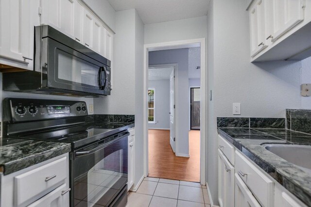 1202 Thorpe Ln Unit 407, San Marcos, TX 78666 - kitchen with black appliances, light tile patterned floors, white cabinets, and dark stone countertops