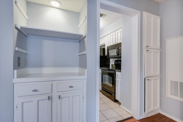 1202 Thorpe Ln Unit 407, San Marcos, TX 78666 - kitchen with black appliances, open shelves, white cabinets, light tile patterned floors, and light countertops