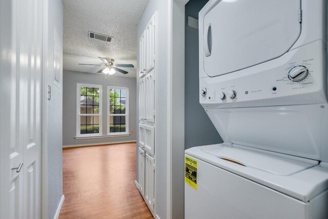1202 Thorpe Ln Unit 407, San Marcos, TX 78666 - laundry area with stacked washing machine and dryer, a textured ceiling, ceiling fan, and light wood-style flooring
