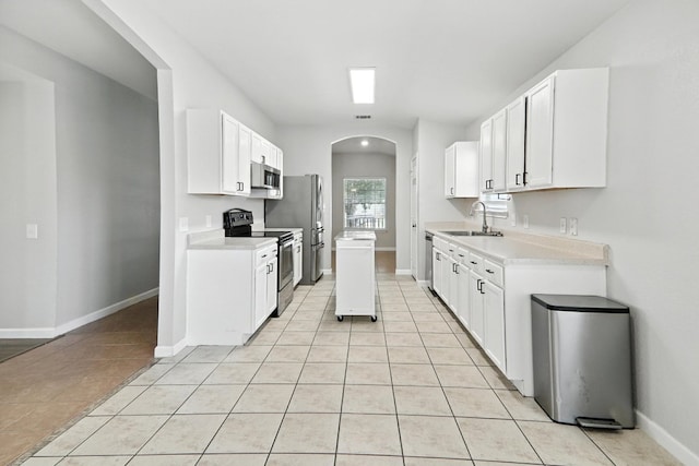 12613 Paloma Blanca Way, Del Valle, TX 78617 - kitchen with appliances with stainless steel finishes, arched walkways, light tile patterned floors, light countertops, and white cabinetry