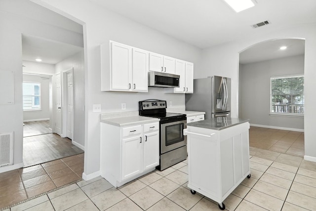 12613 Paloma Blanca Way, Del Valle, TX 78617 - kitchen featuring appliances with stainless steel finishes, arched walkways, light tile patterned flooring, white cabinets, and recessed lighting