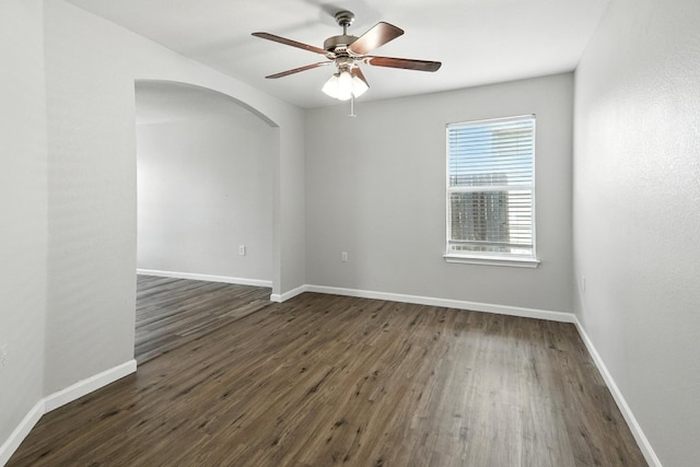 12613 Paloma Blanca Way, Del Valle, TX 78617 - unfurnished room with arched walkways, ceiling fan, and dark wood-type flooring