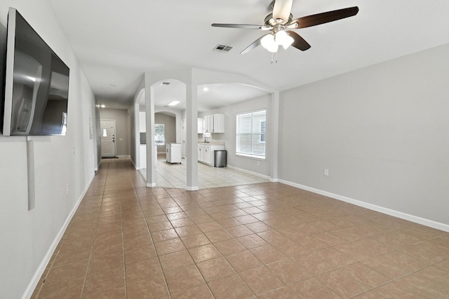 12613 Paloma Blanca Way, Del Valle, TX 78617 - unfurnished living room with light tile patterned floors, arched walkways, and ceiling fan