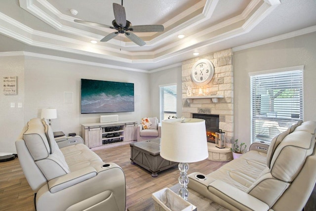 5106 La Piedra Ln, Killeen, TX 76549 - living area featuring a tray ceiling, ornamental molding, light wood-style flooring, a stone fireplace, and a ceiling fan