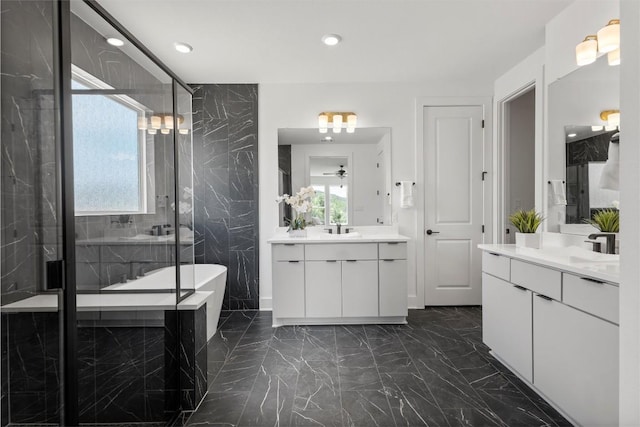 5316 Bellano Bnd, Leander, TX 78641 - full bathroom featuring marble tiled floors, two vanities, a freestanding tub, a marble finish shower, and recessed lighting