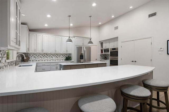 1501 Johnny Miller Trl, Austin, TX 78746 - kitchen with stainless steel appliances, tasteful backsplash, a peninsula, lofted ceiling, and recessed lighting