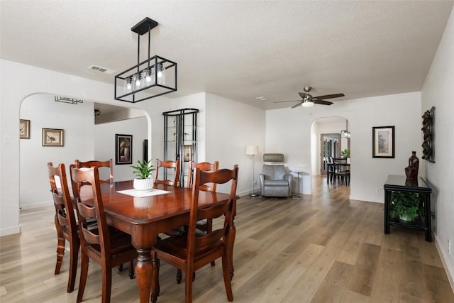 1501 Johnny Miller Trl, Austin, TX 78746 - dining space with arched walkways, a textured ceiling, light wood-style floors, and a ceiling fan
