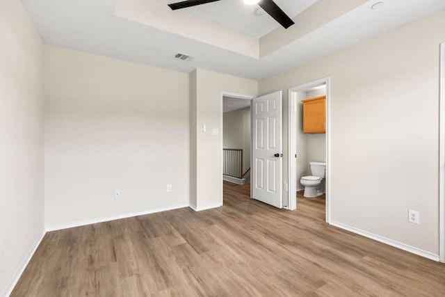 9201 Brodie Ln Unit 1002, Austin, TX 78748 - unfurnished bedroom featuring light wood finished floors, a tray ceiling, and ensuite bath