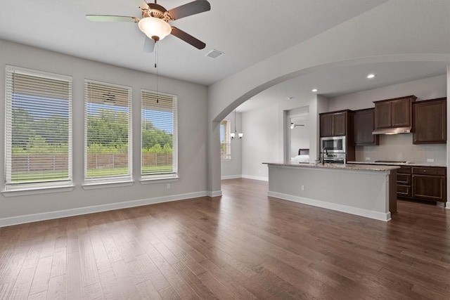 416 Hereford Loop, Hutto, TX 78634 - kitchen with stainless steel appliances, arched walkways, a ceiling fan, an island with sink, and dark wood-style floors