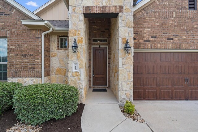 416 Hereford Loop, Hutto, TX 78634 - property entrance with board and batten siding, stone siding, an attached garage, brick siding, and concrete driveway