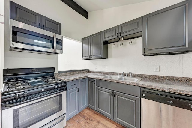 1010 W 23rd St Unit 2, Austin, TX 78705 - kitchen featuring stainless steel appliances, gray cabinets, light wood-style flooring, and dark countertops