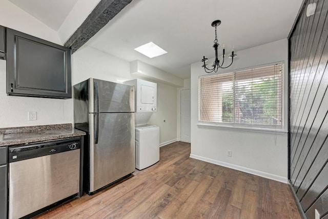 1010 W 23rd St Unit 2, Austin, TX 78705 - kitchen with stainless steel appliances, stacked washer / dryer, a skylight, and wood finished floors
