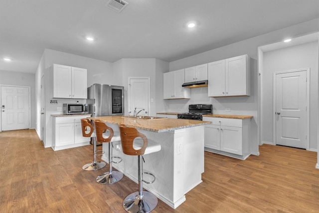 2961 Brogan Crk, New Braunfels, TX 78130 - kitchen with stainless steel appliances, recessed lighting, an island with sink, white cabinets, and a kitchen bar
