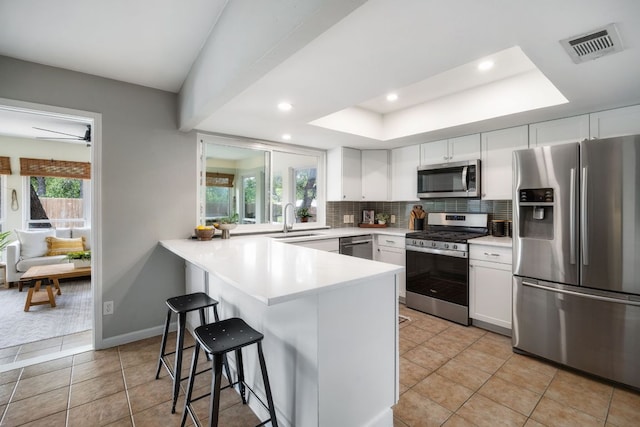 1406 Radam Cir, Austin, TX 78745 - kitchen with appliances with stainless steel finishes, a peninsula, a kitchen breakfast bar, recessed lighting, and white cabinetry