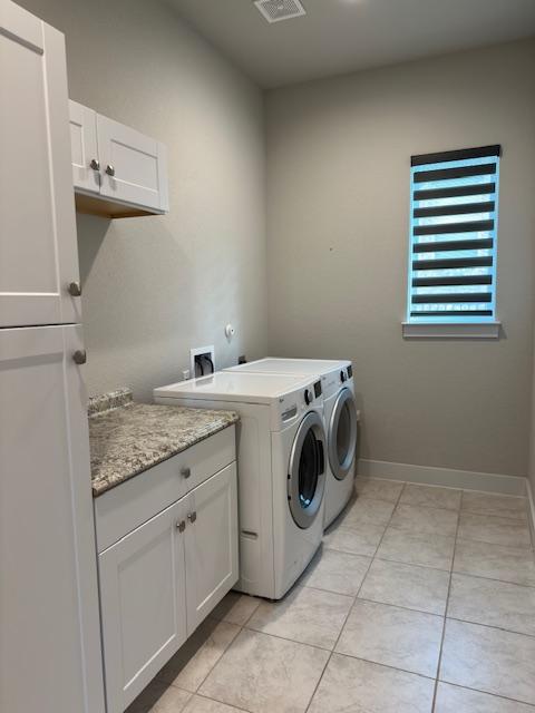 900 Elenora Dr, Leander, TX 78641 - laundry room featuring cabinet space, light tile patterned floors, and washing machine and dryer