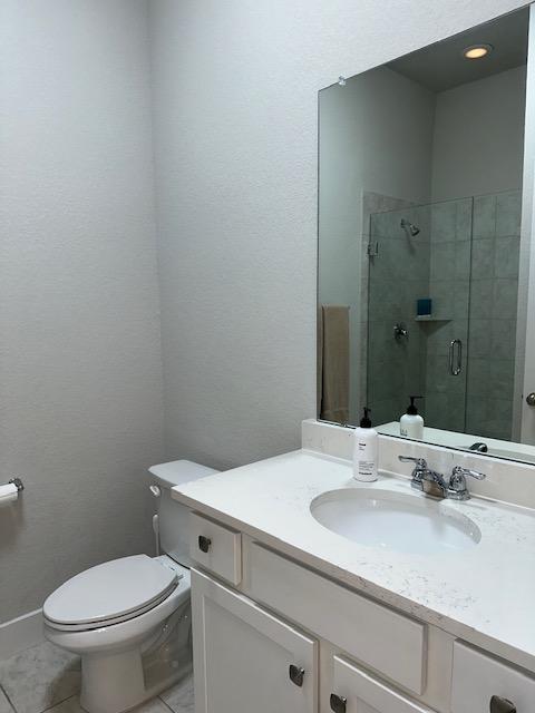 900 Elenora Dr, Leander, TX 78641 - bathroom featuring vanity, a stall shower, tile patterned floors, and a textured wall