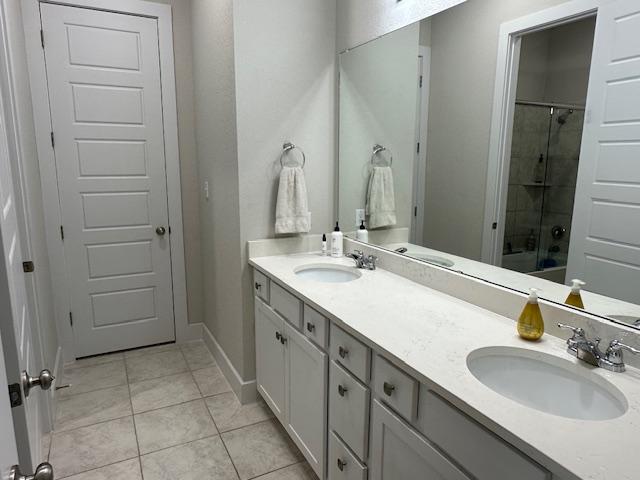 900 Elenora Dr, Leander, TX 78641 - bathroom featuring a shower with shower door, double vanity, and tile patterned floors